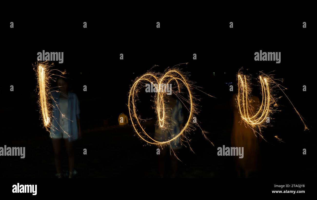 A word i LOVE u was written with sparkler firework on black background Stock Photo
