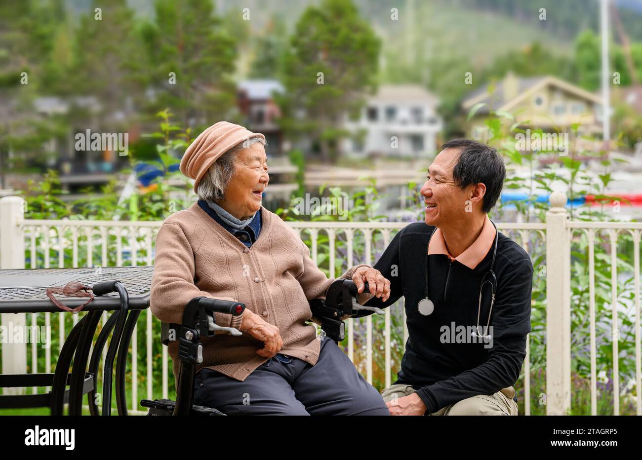 Male Doctor visiting senior patient at home. Patient sitting on the mobility walker in the backyard. Stock Photo