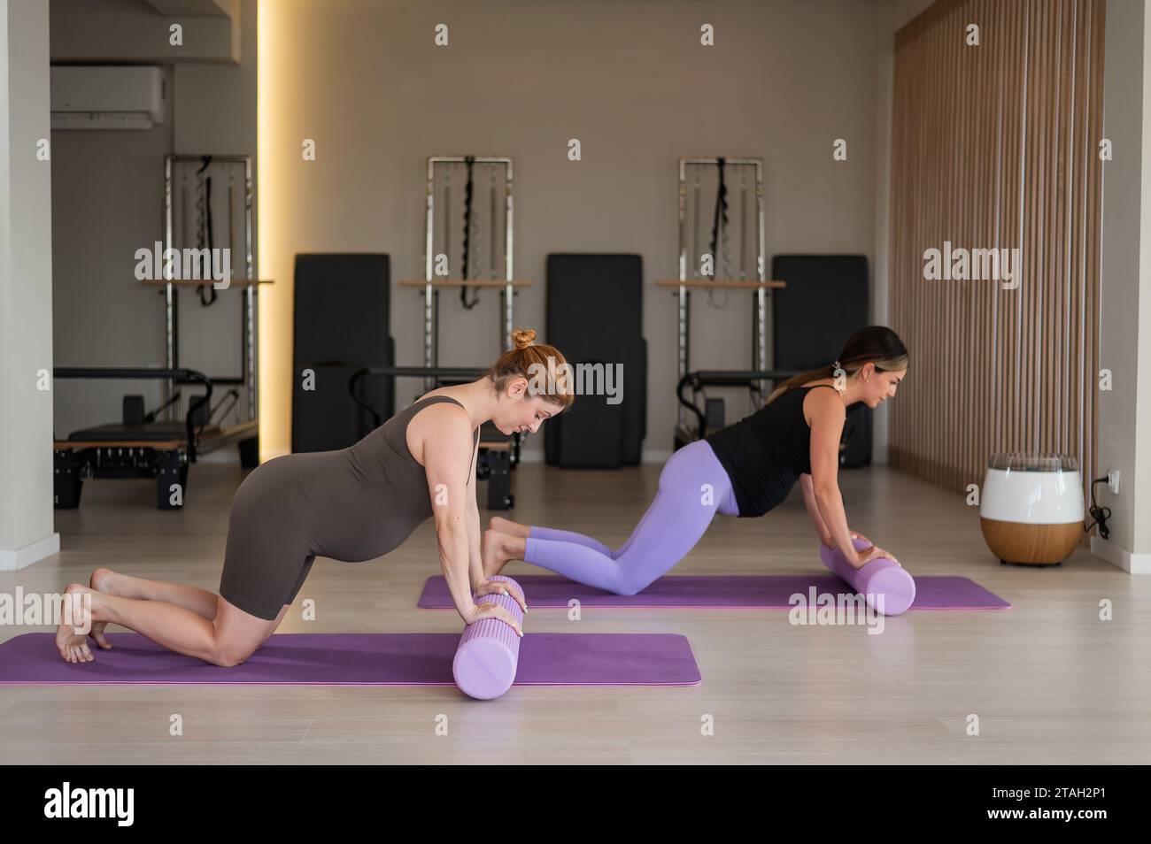 Two pregnant women do a plank with bolsters. Yoga for pregnant women