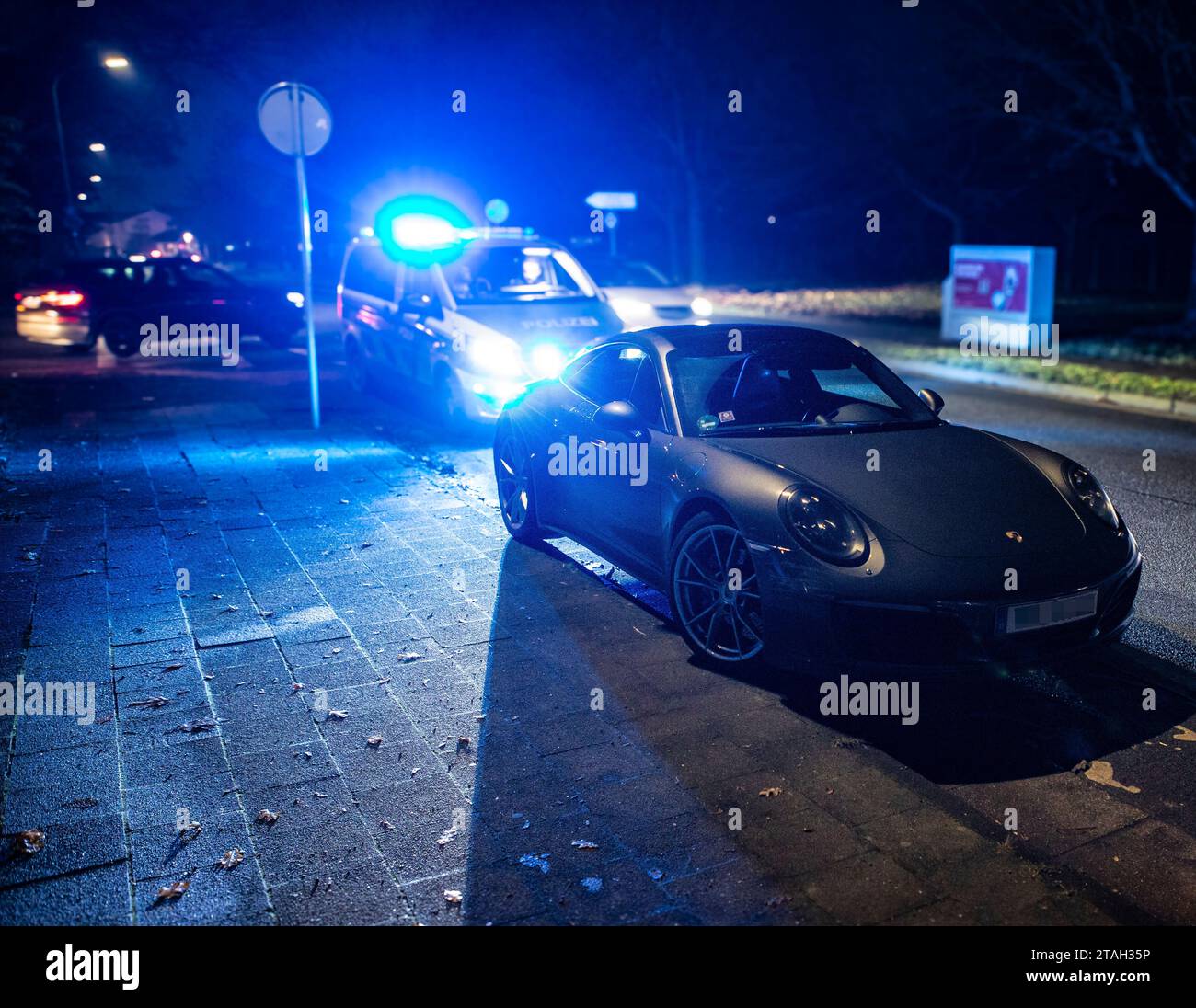 Ein Streifenwagen der Polizei mit eingeschalteten Blaulicht hinter einem Porsche Carrera 911 S4 nach einem Verkehrsunfall mit Bagatellschaden. Stock Photo