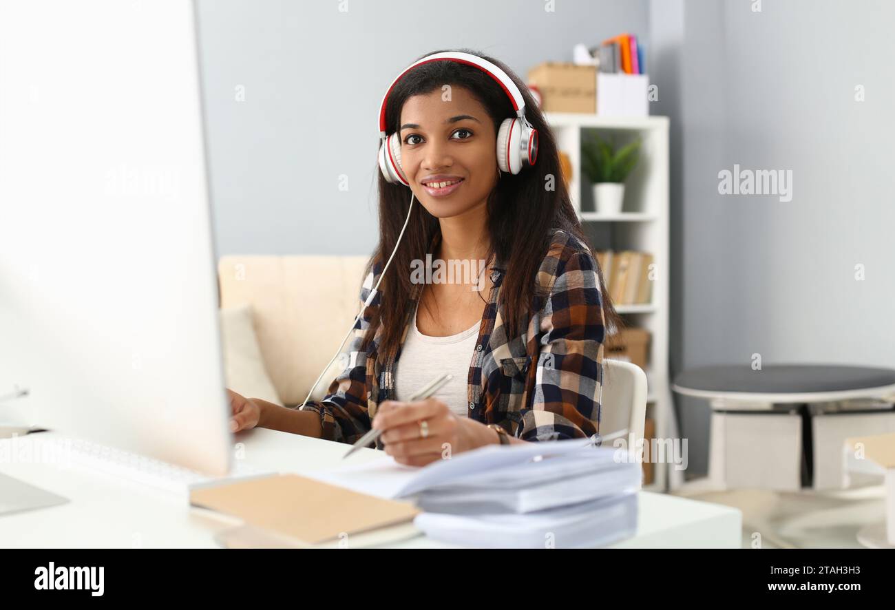African female student wears headphones studying alone at home office ...