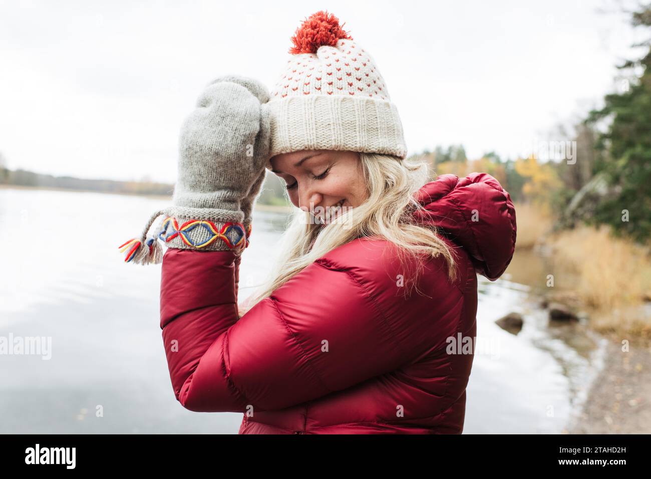 woman with nordic gloves on smiling by the sea in Sweden Stock Photo