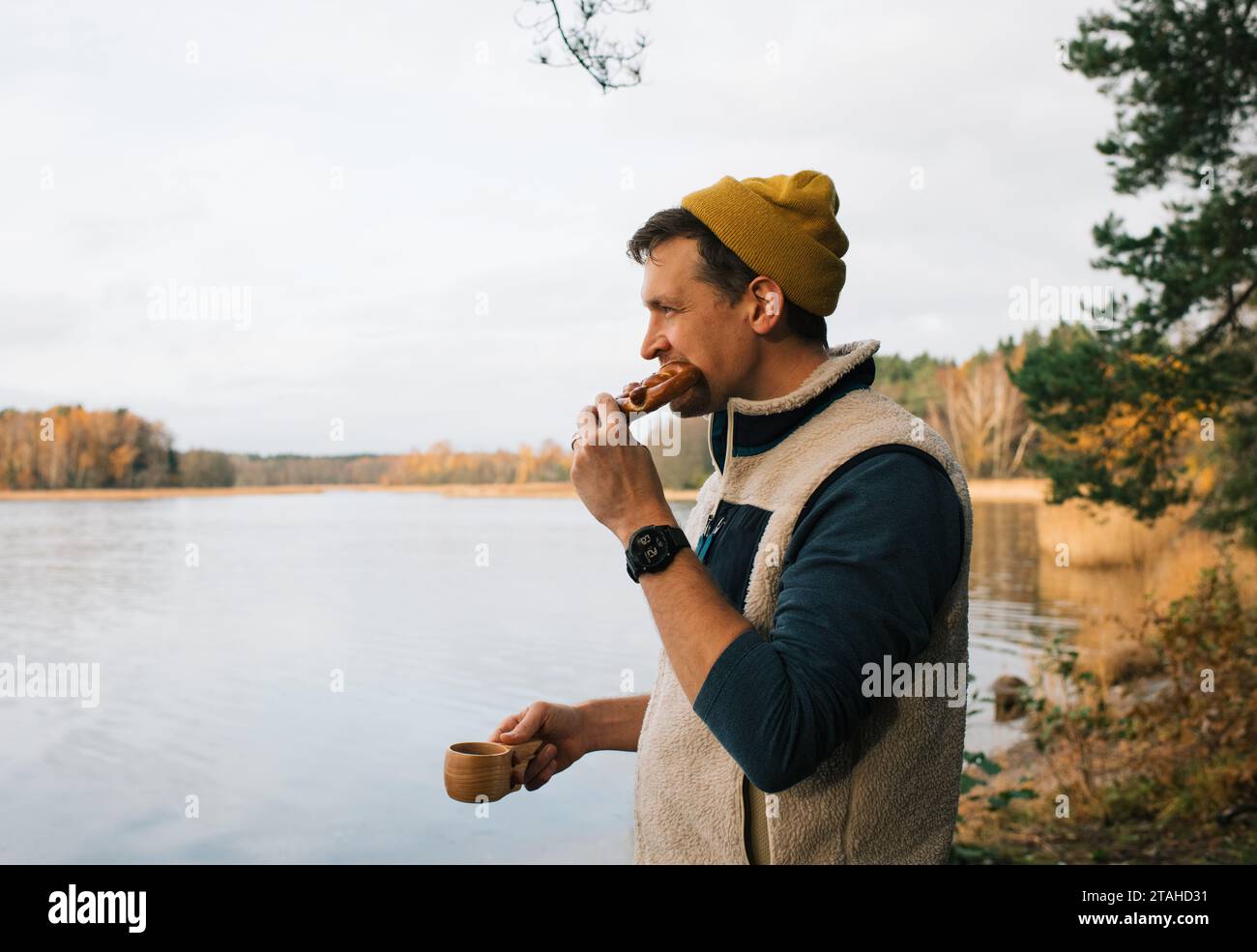 man drinking coffee and eating a pretzel by the sea in Sweden Stock Photo