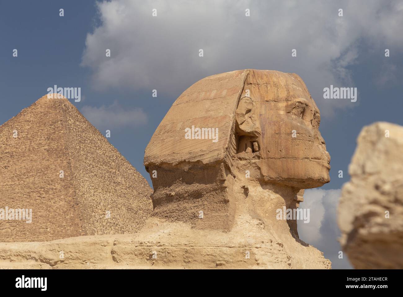 Zoom of the Head of the Sphinx of Gyza with pyramid behind Stock Photo