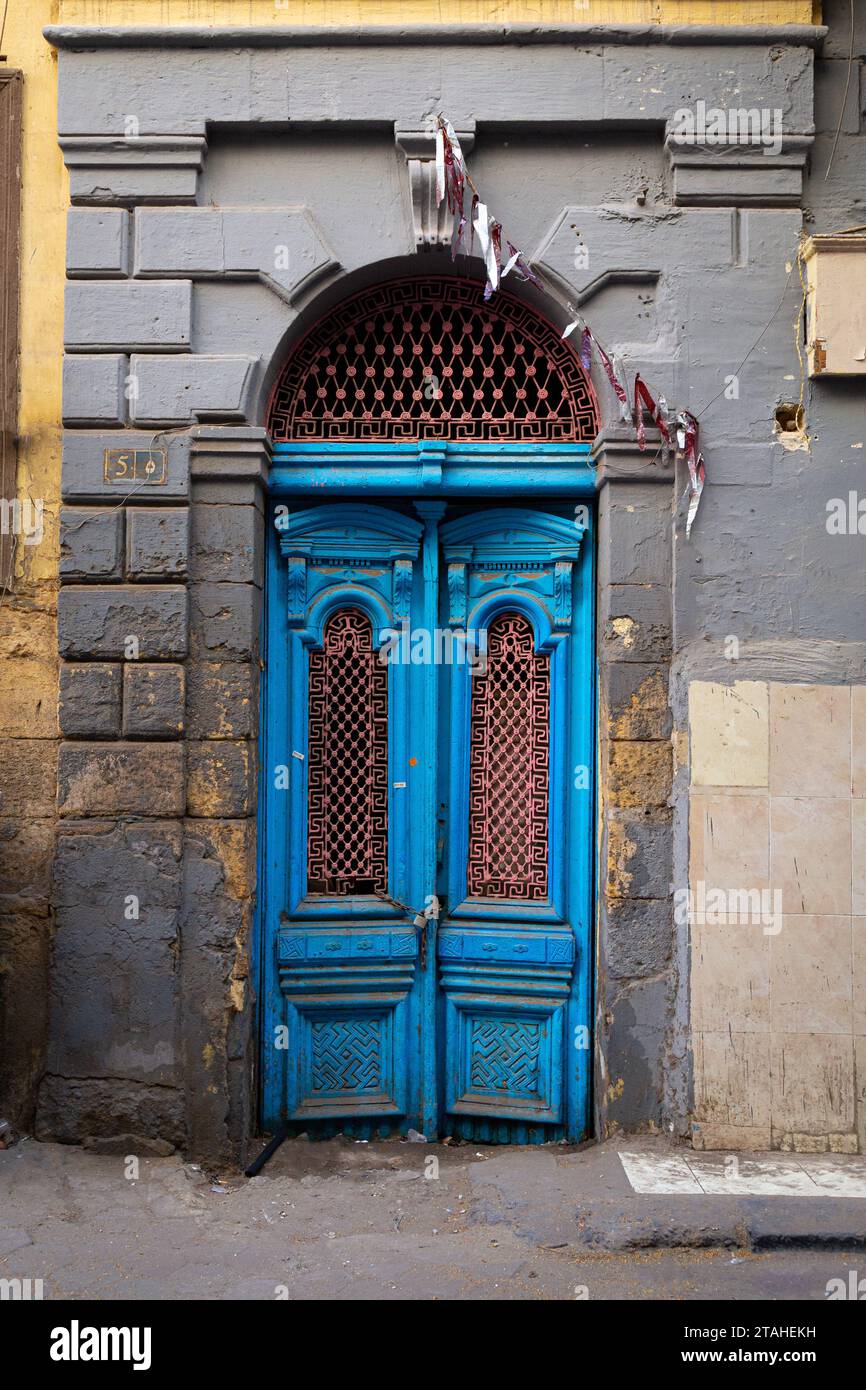 Old electric-blue wooden door on grey façade Stock Photo