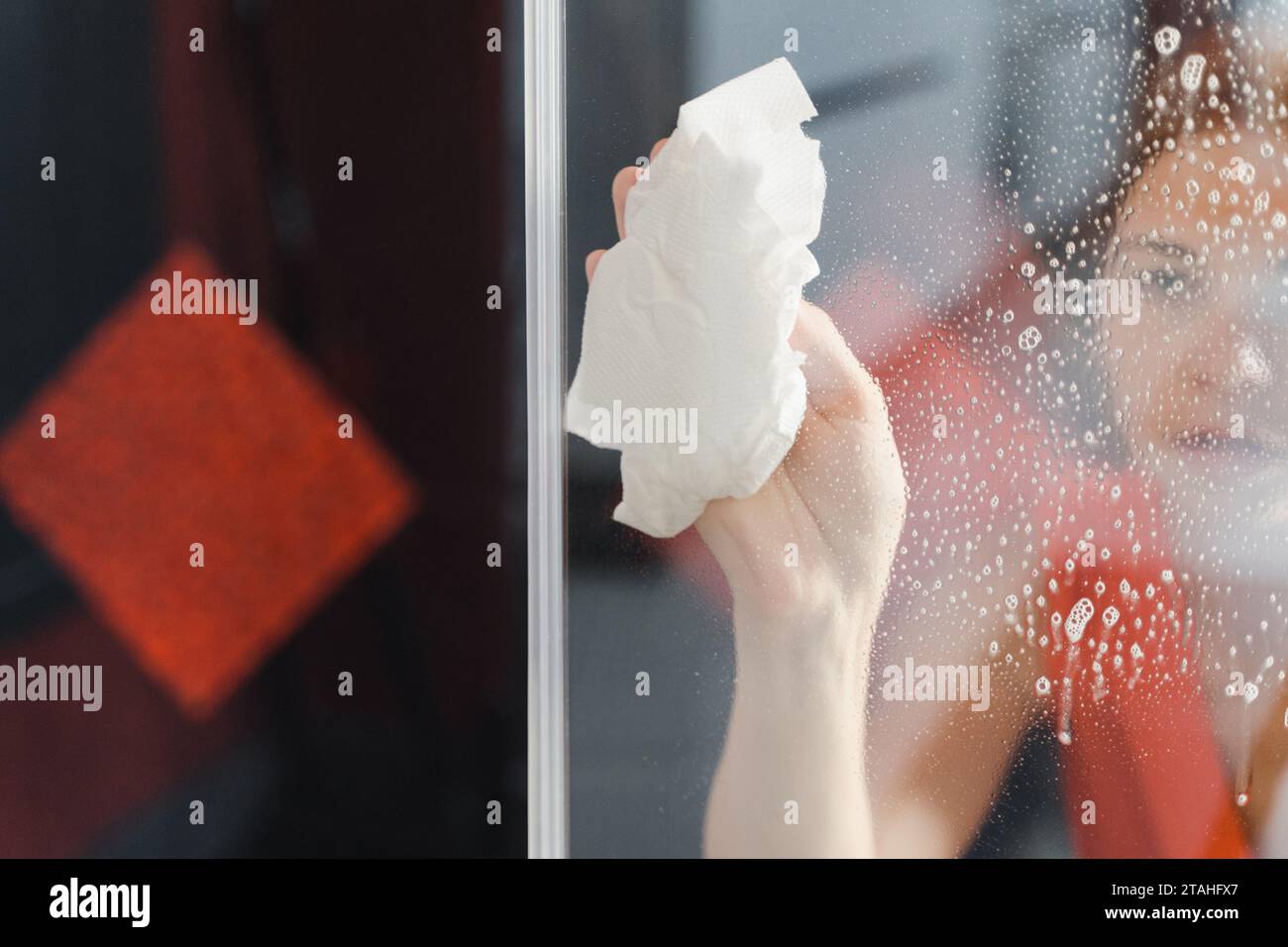 Woman cleaning the house, wiping glass door Stock Photo