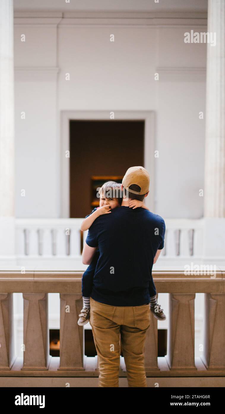 Dad holds smiling toddler son inside framed white doorway Stock Photo