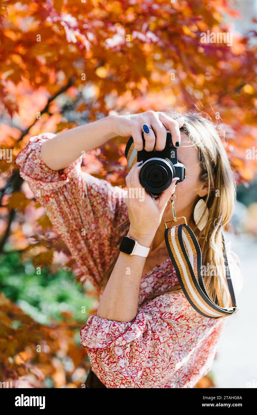 Woman takes photograph in fall colored forest with digital SLR camera Stock Photo