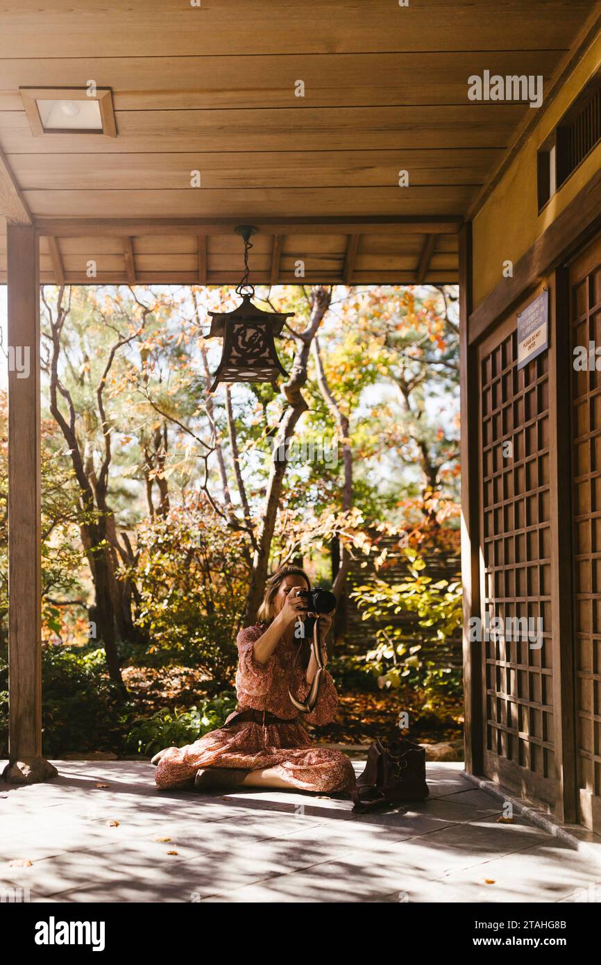 Woman takes photographs of Japanese style building outside in fall Stock Photo