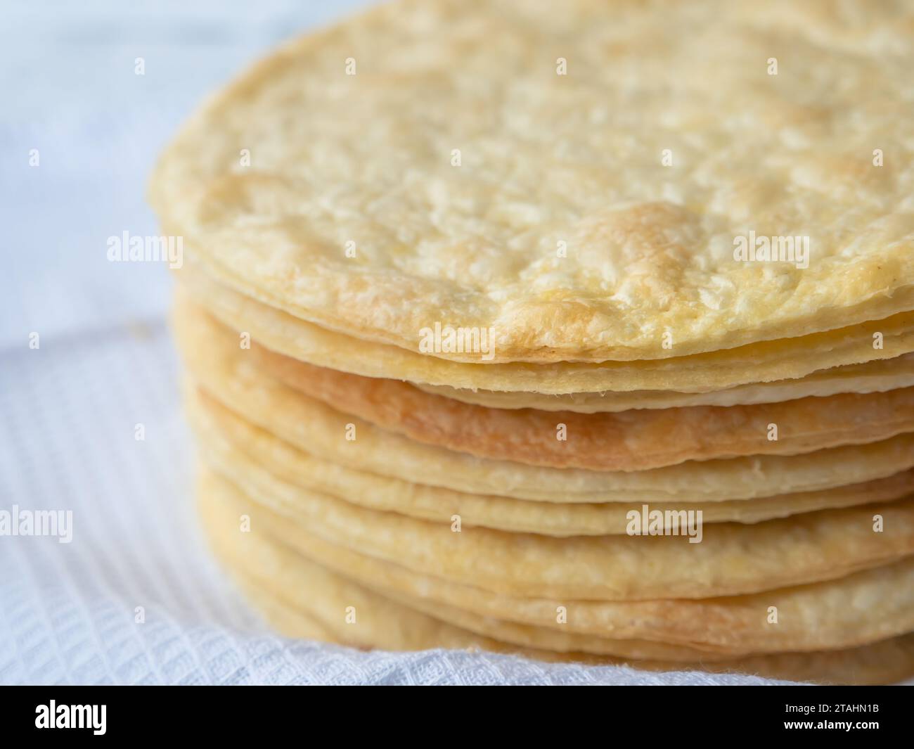 Closeup of a pile of baked thin round buttery layers on a white waffle towel ready to make a shortcrust puff pastry Napoleon cake. Stock Photo