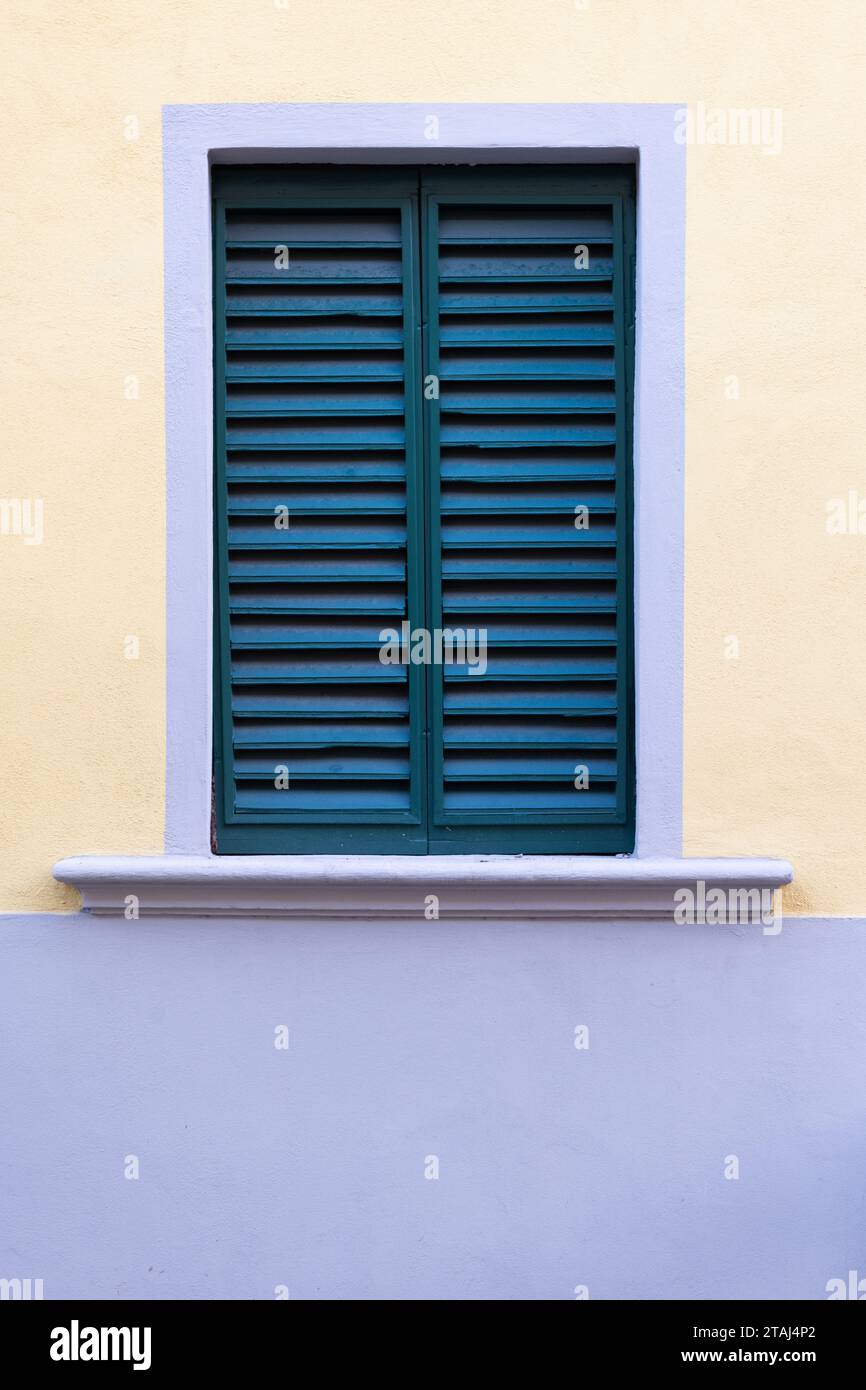 Blue shutters set against a purple and yellow wall in Florence, Tuscany, Italy. Stock Photo