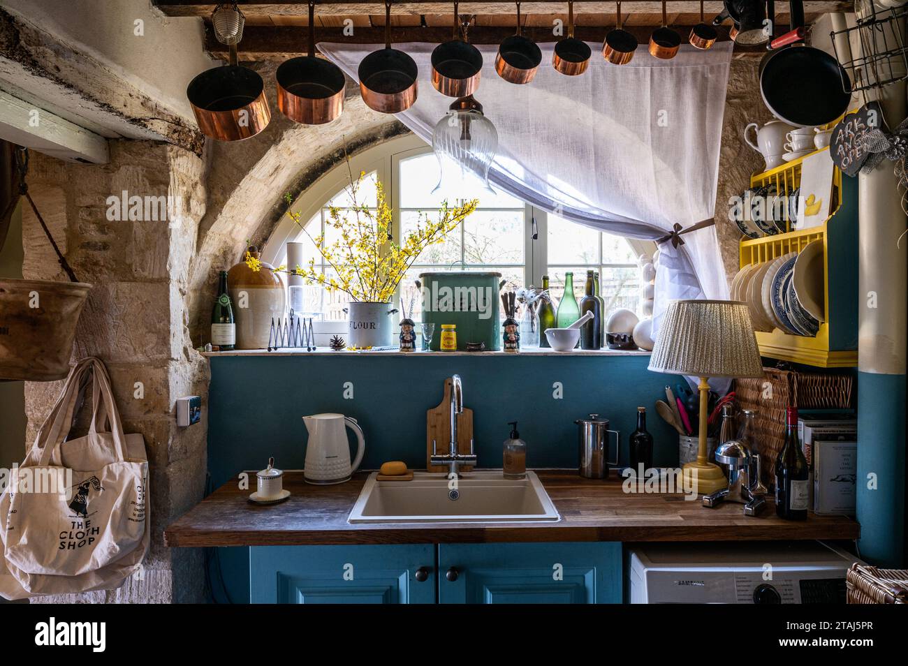 Copper saucepans hang above kitchen unit at original Cotswolds stone