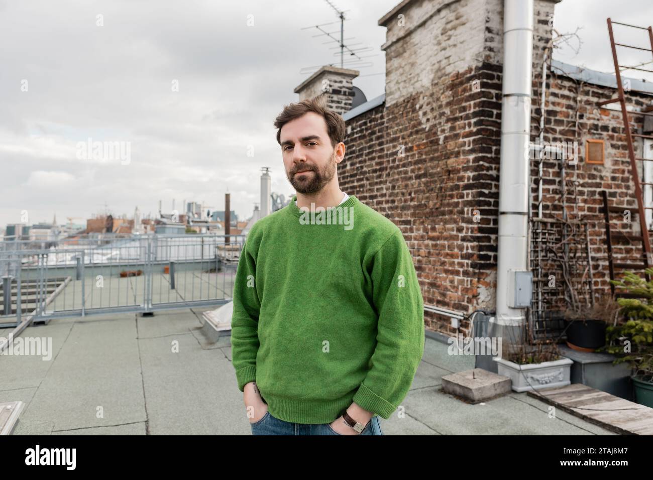 Bearded man standing on rooftop terrace of house with blurred cityscape at background in Vienna Stock Photo