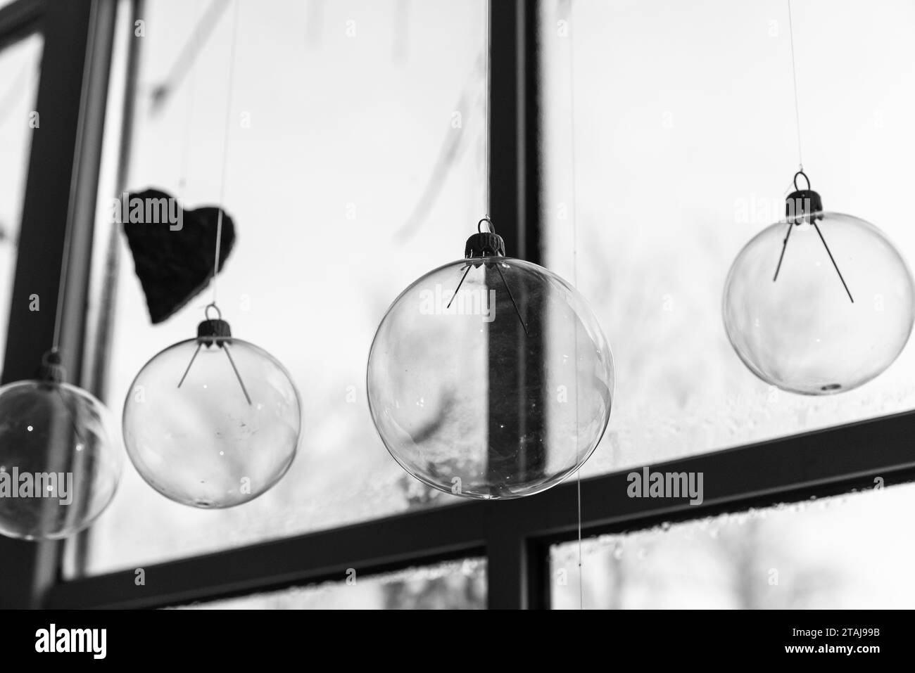 Transparent glass balls hang in front of a window, Christmas decoration abstract black and white photo Stock Photo