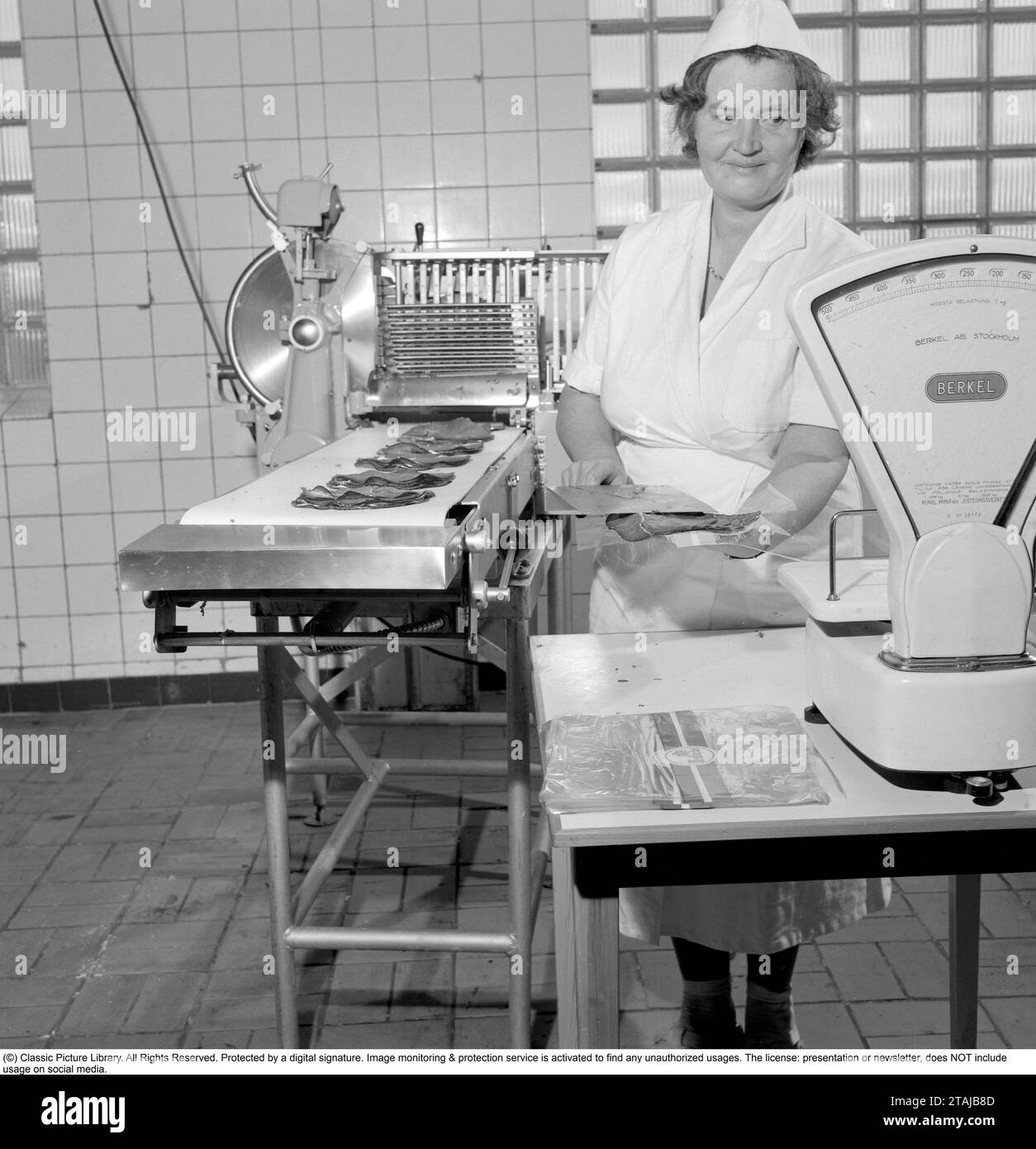 The slaughterhouse area, an industrial area in the Johanneshov district in Söderort within Stockholm municipality, which was inaugurated in January 1912, where many companies in the food industry had their premises. Here a woman slicing, weighing and packaging meat on September 29, 1960. Conard ref 4325 Stock Photo