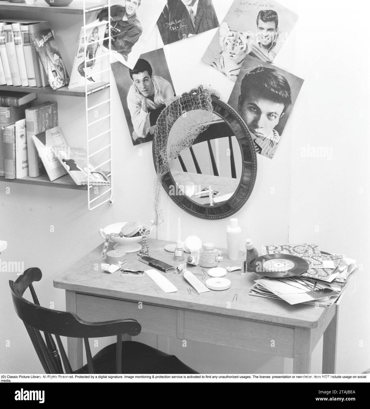 In the 1950s. A teenagers room with a desk with make up and single records. On the wall pictures of the teen male idols of the time. Sweden 1959 Stock Photo