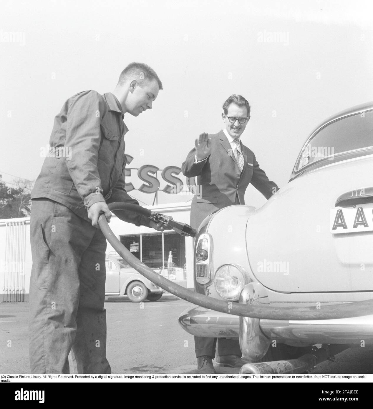 Car owner of the 1950s. A man with a service man at a petrol station is getting help to fill the tank. 1959 Stock Photo