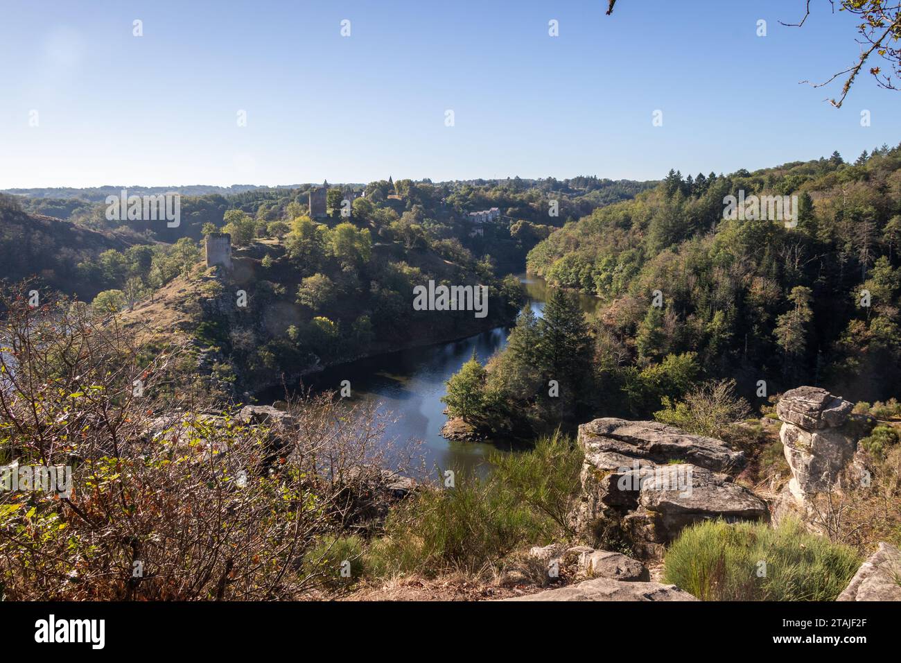 A  landscape view (Rocher de la Fileuse) looking down at the River Sedelle with fort ruins near Crozant, Creuse, France with rocks in the foreground. Stock Photo