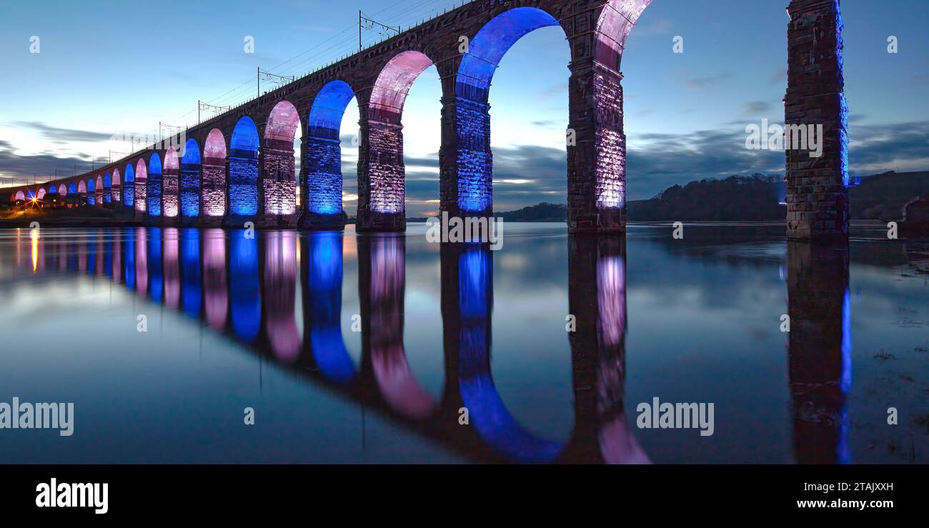 View at dusk of the floodlit Royal Border Bridge in Berwick upon Tweed reflected in the River Tweed on a clear winter night in Northumberland Stock Photo