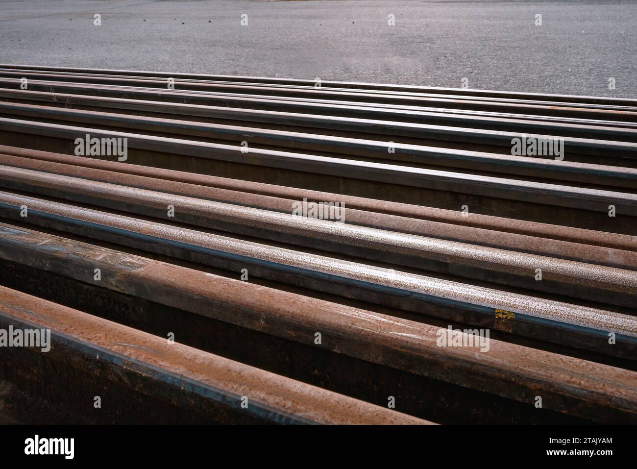 Many used rusty rails of different length stored at a ground for old rails replacement. Diagonal placement photo Stock Photo