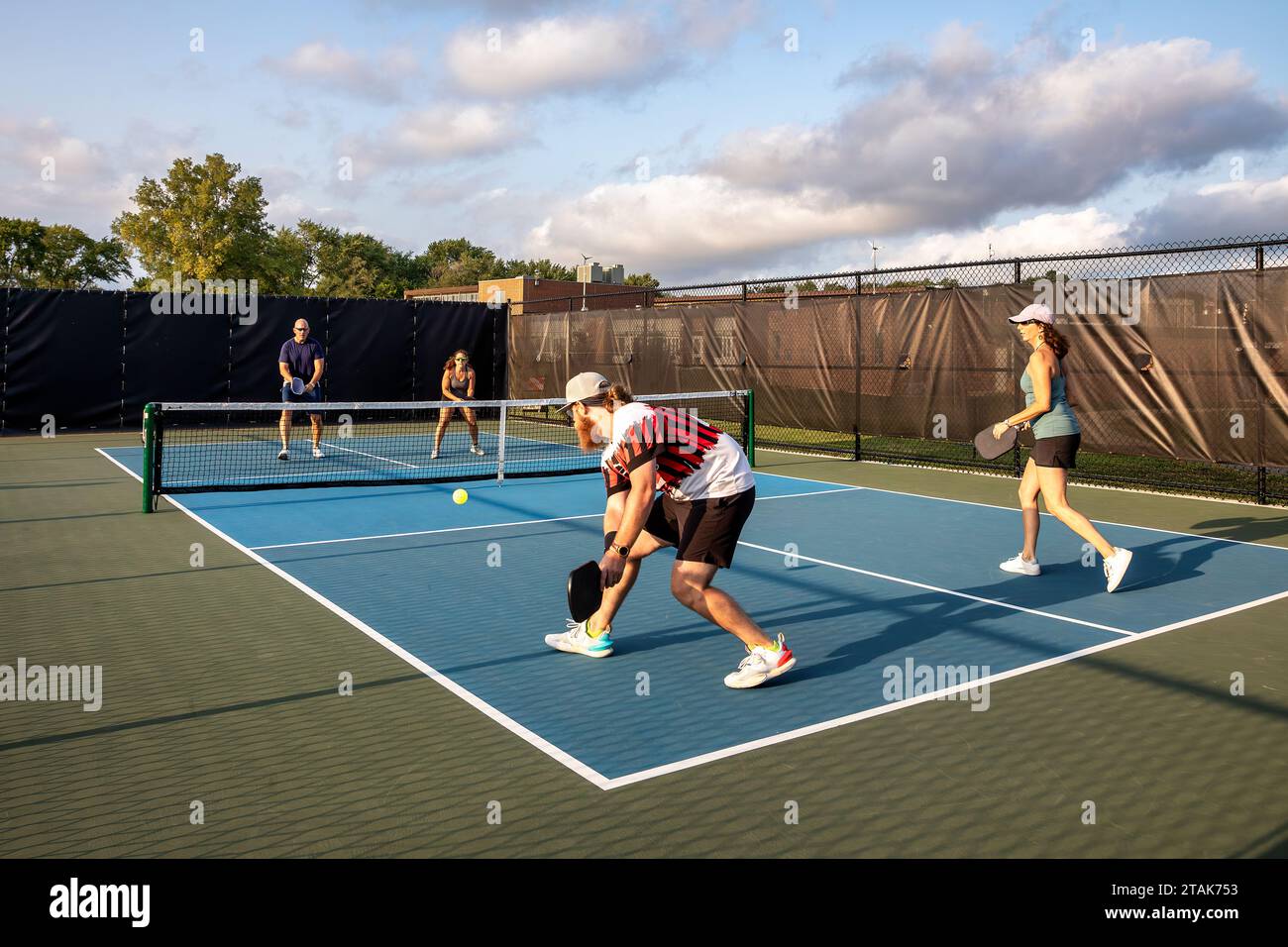 Four pickleball players rally against each other with two at the net ...