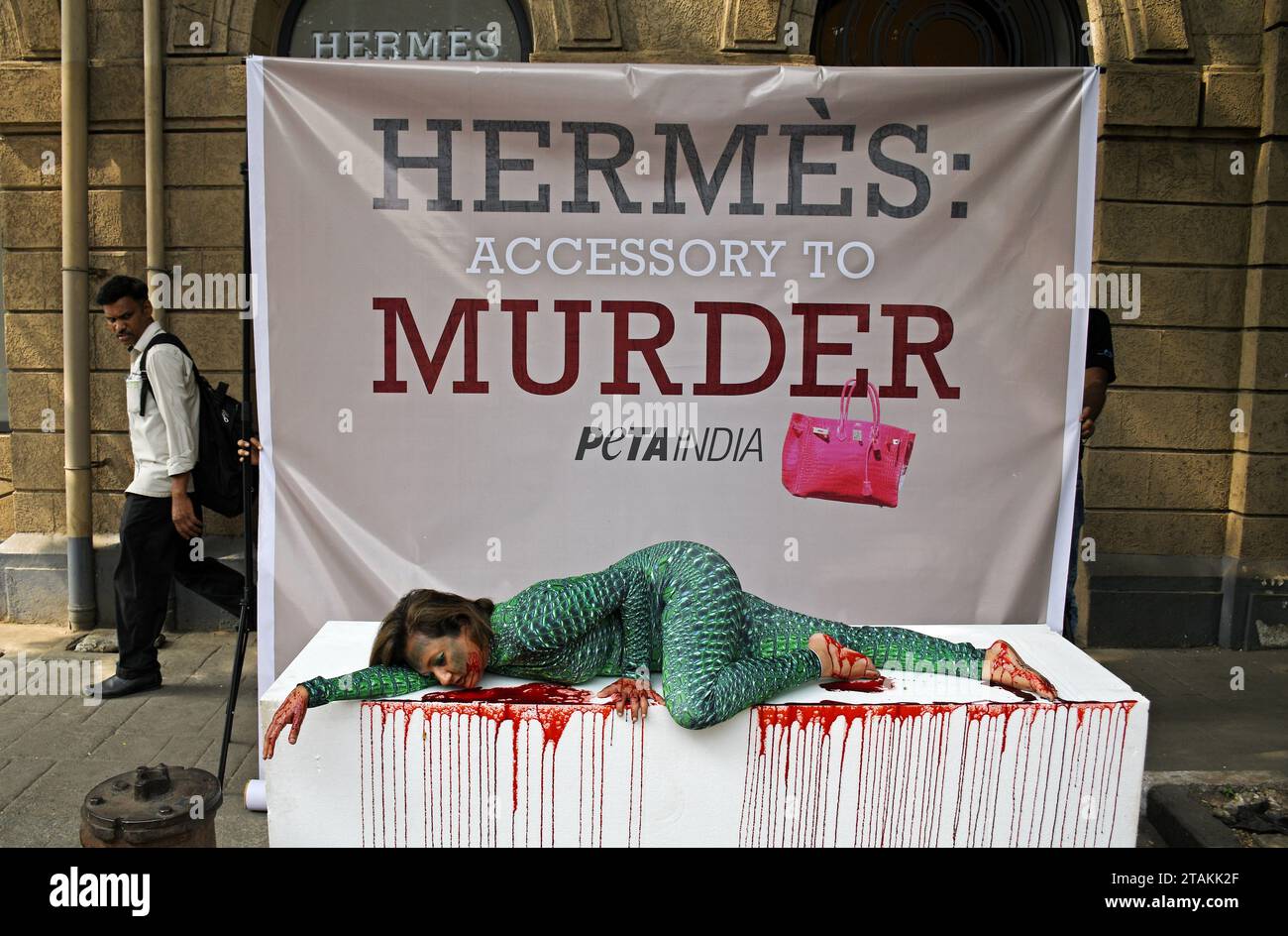 Mumbai, India. 01st Dec, 2023. Activist for the Ethical Treatment of Animals (PETA India) director Poorva Joshipura wearing a alligator-skin costume and lying in a pool of (fake) blood on a thermocol table is seen outside the French fashion store 'Hermes' in Mumbai. The PETA India director Poorva Joshipura calls on the French fashion house 'Hermes' to ban the use of alligators, crocodiles and other exotic animals who are tormented and killed for their skins to make leather bags and accessories by the brand. (Photo by Ashish Vaishnav/SOPA Images/Sipa USA) Credit: Sipa USA/Alamy Live News Stock Photo