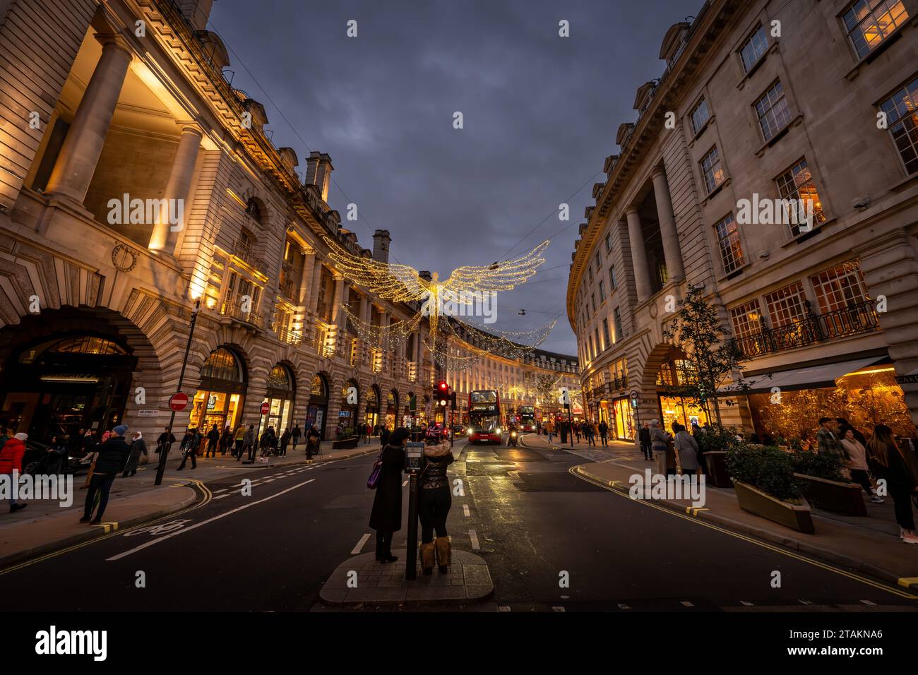 London, UK - Nov 20 2023: Regent Street in central London with Christmas lights overhead. People stand in the middle of the road taking photographs. Stock Photo