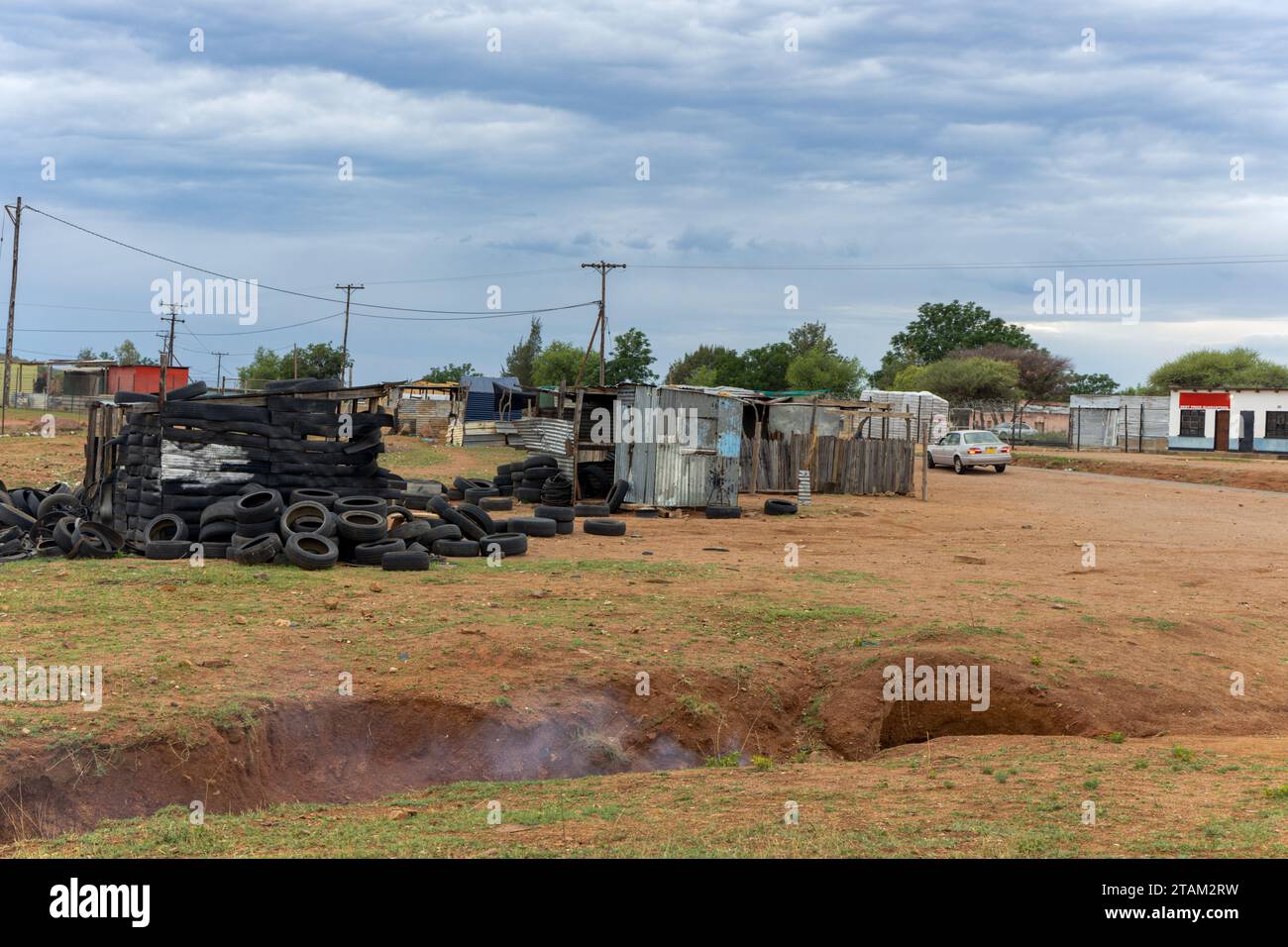 township informal settlement, shanty town made of corrugated iron sheets and tiers, smoking ditch in front Stock Photo