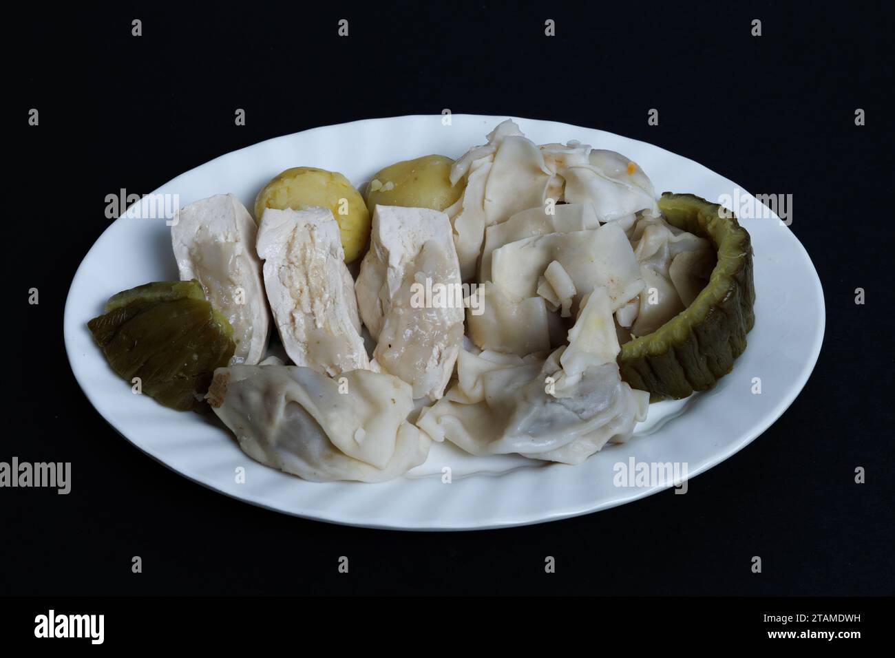 Siomay Bandung or steamed dumplings, Indonesian traditional street food. no peanut souce. on white plate isolated on black background. Stock Photo