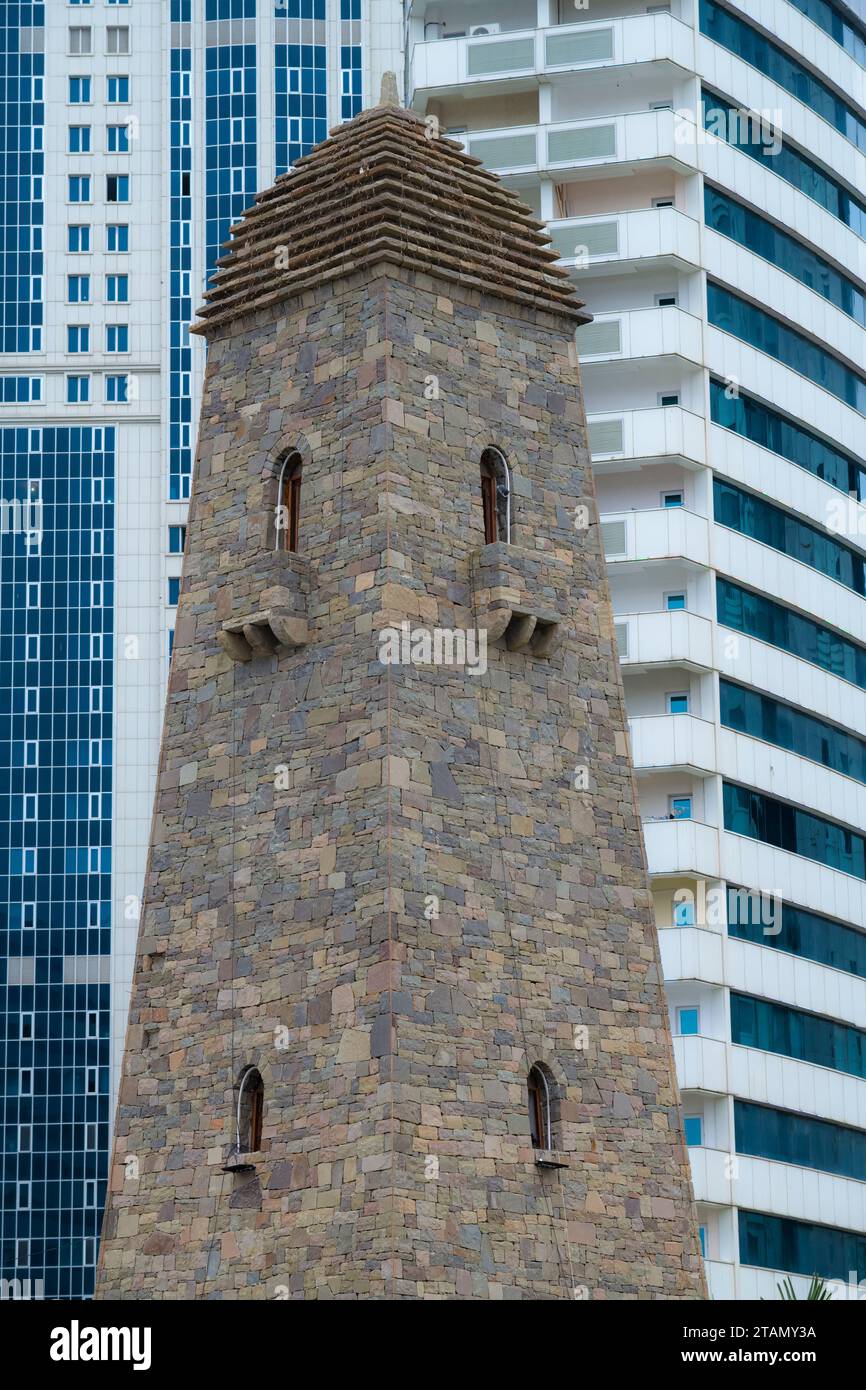 Traditional Vainakh tower against the background of a modern high-rise building. Grozny, Chechnya. Russian Federation Stock Photo