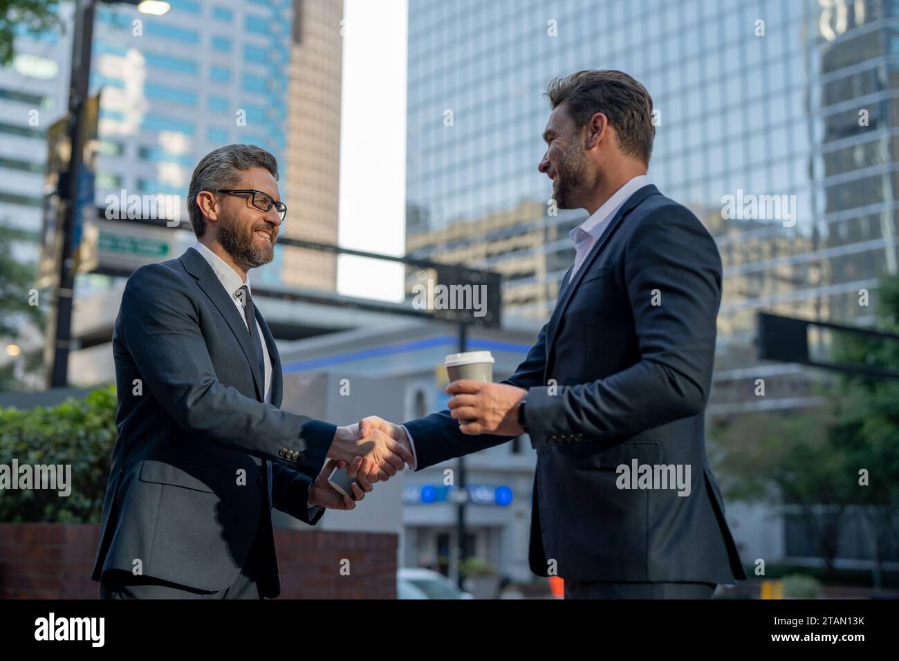 American businessman shaking hands with partner. Businessmen in suit shaking hands outdoors. Handshake between two businessmen. wo business men had Stock Photo