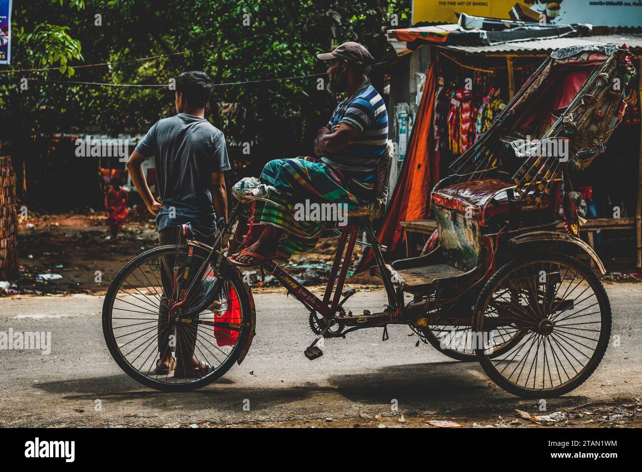 A rickshaw puller, resting on a traditional Bengali vehicle known as a