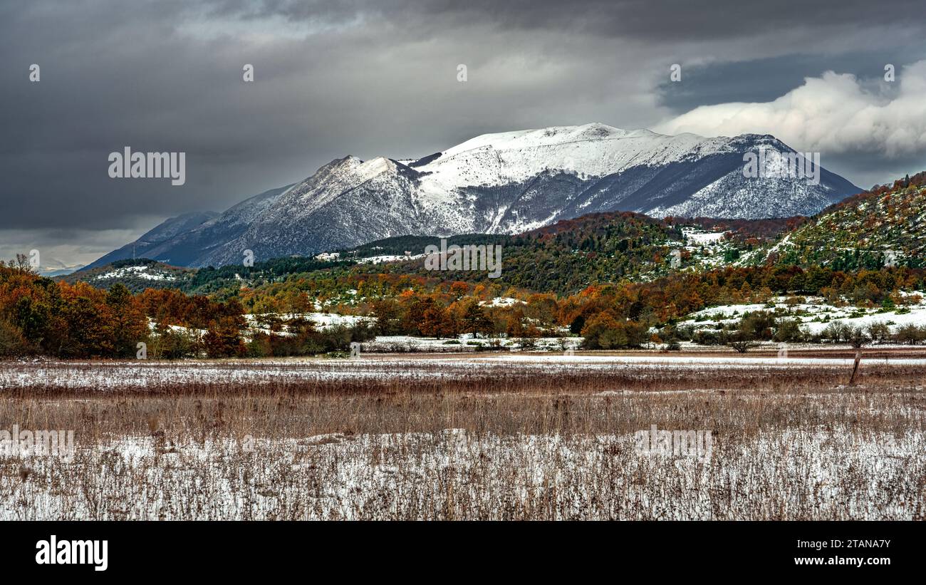 the snow-covered meadows of Piano Cerreto and the woods with the autumn colors of the Bosco di Sant'Antonio. In the background Mount Morrone. Abruzzo Stock Photo