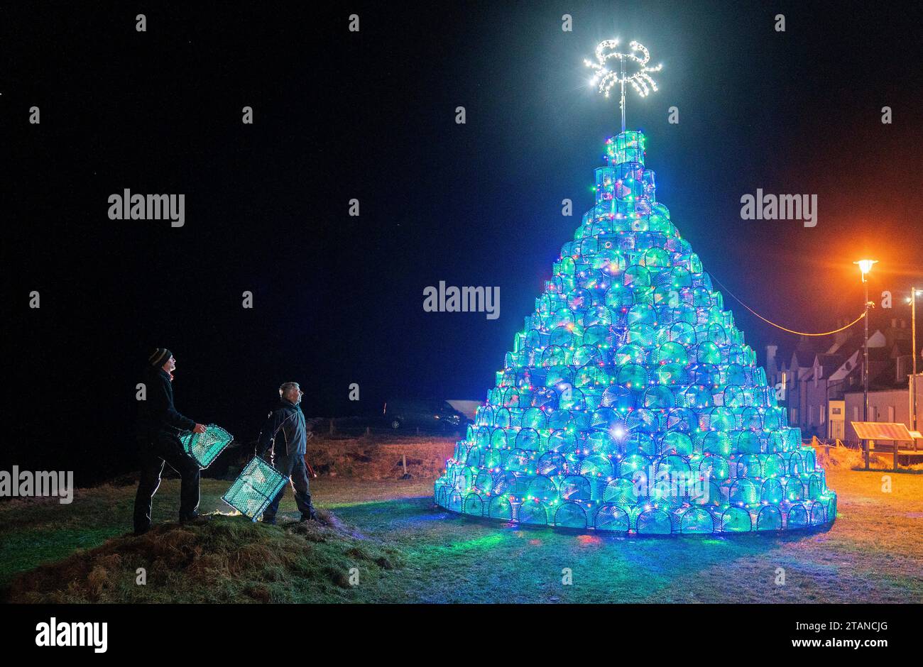 Gordon Wink (right) and Simon Eltingham alongside the fishing creel Christmas tree they helped to design and build on the harbour-side in Ullapool, Wester Ross. Picture date: Friday December 1, 2023. Stock Photo