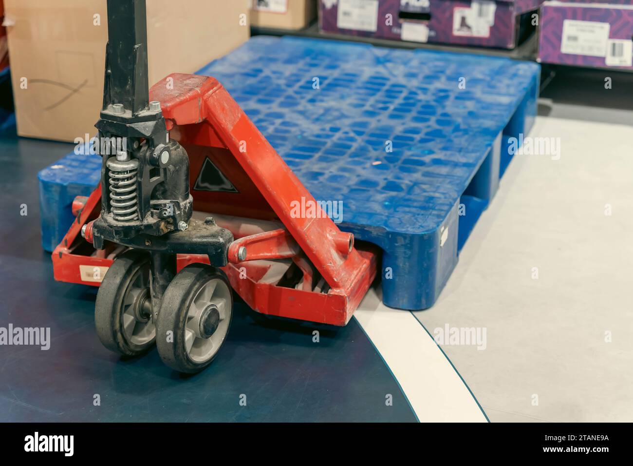 A manual hydraulic pallet lift stands on the floor of the store's