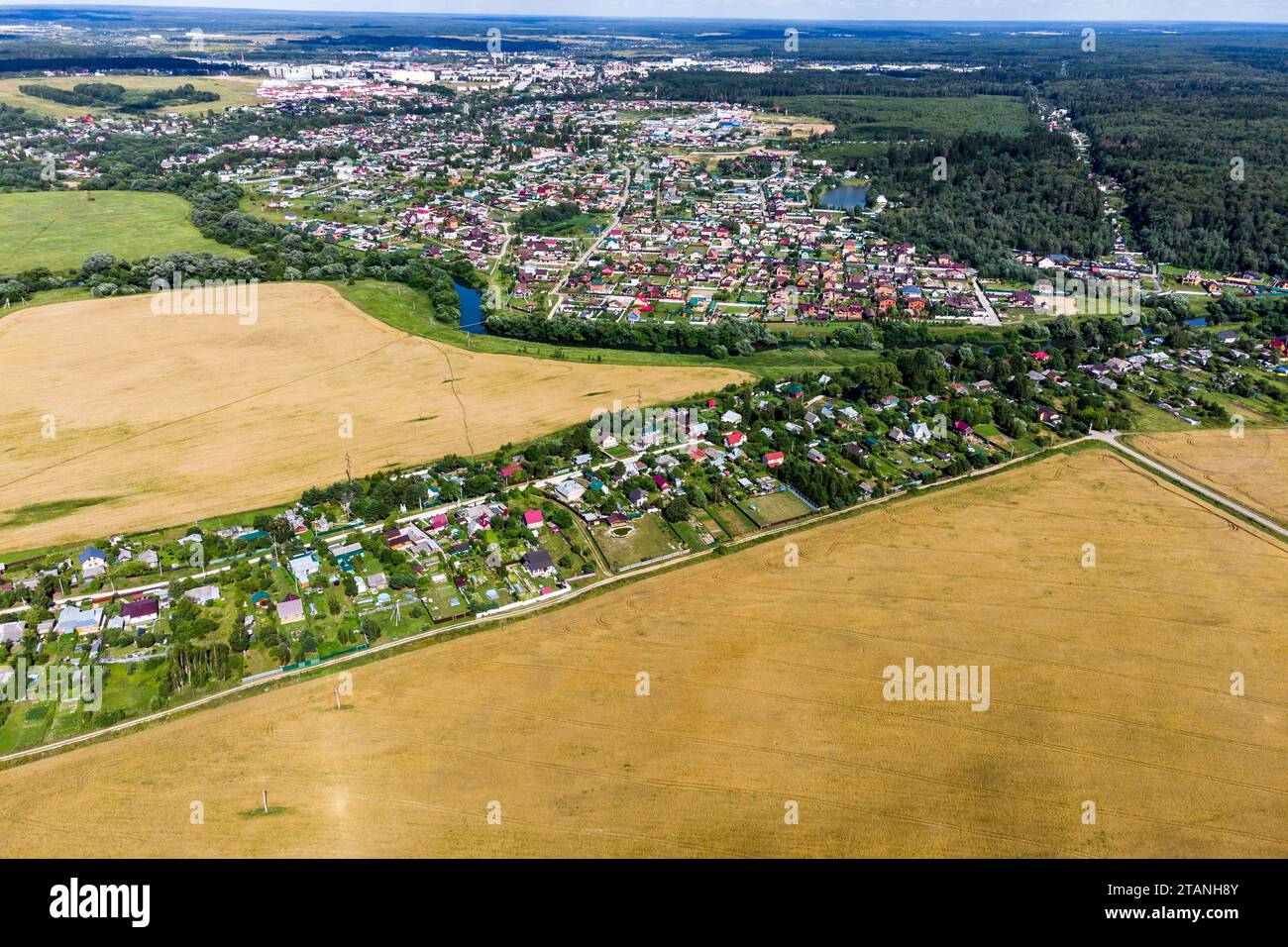 View from a high altitude of rural and rural buildings surrounded by fields and forests Stock Photo