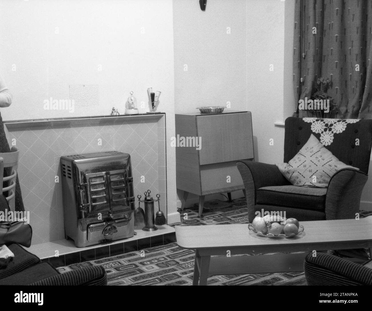 Archive snapshot of a typical 1950s British lounge or front room or living room with fireplace, armchair, sideboard and coffee table Stock Photo
