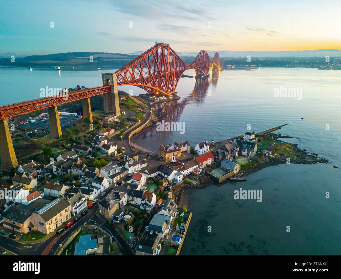 Aerial view from drone at dusk of North Queensferry village beside the Forth Bridge crossing the Firth of Forth, Fife, Scotland, UK Stock Photo