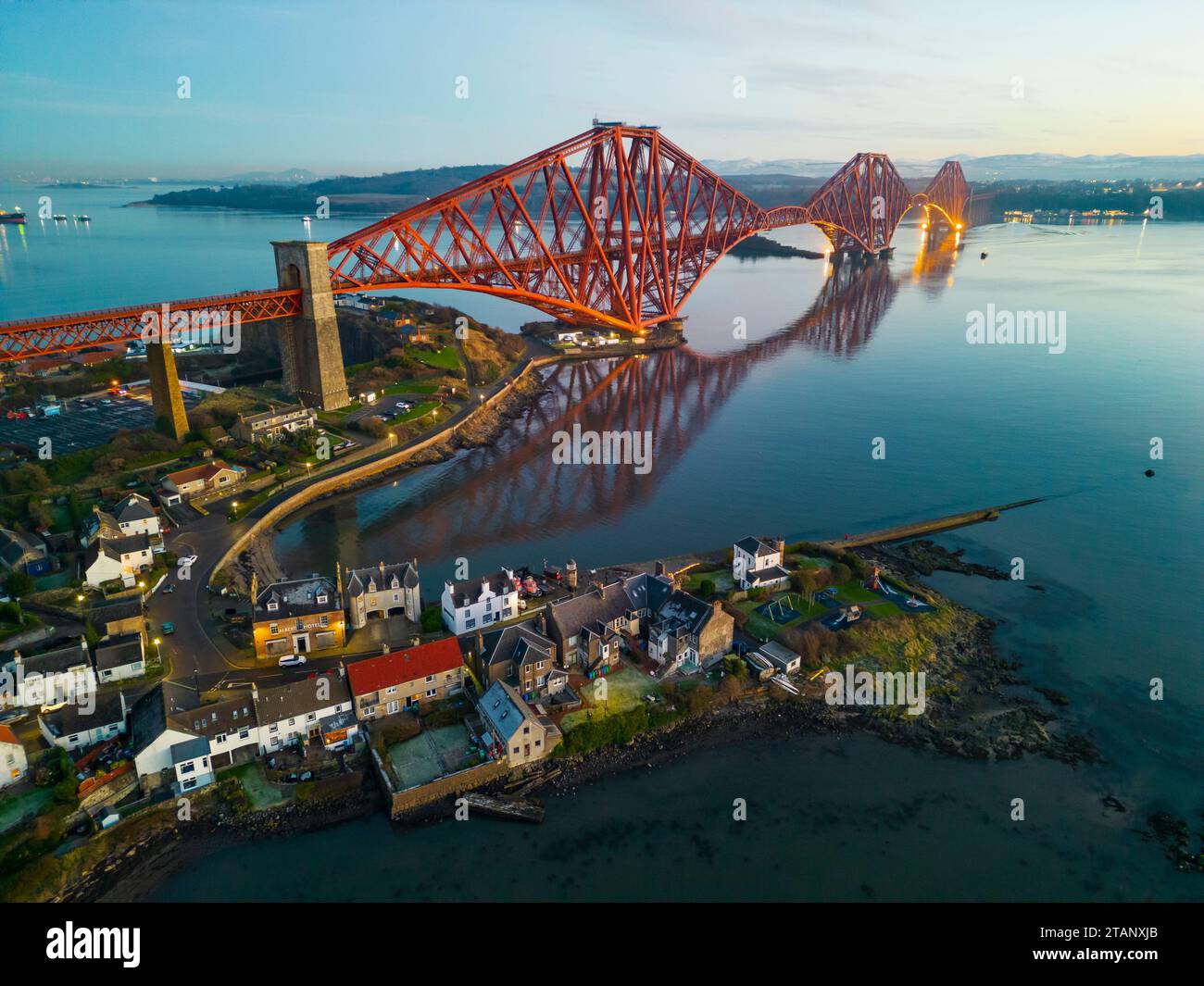 Aerial view from drone at dusk of North Queensferry village beside the Forth Bridge crossing the Firth of Forth, Fife, Scotland, UK Stock Photo