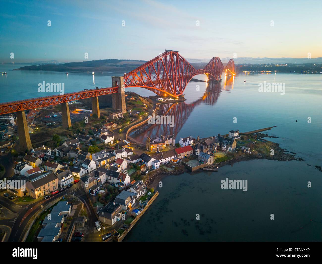 Aerial view from drone at dusk of North Queensferry village beside the Forth Bridge crossing the Firth of Forth, Fife, Scotland, UK Stock Photo