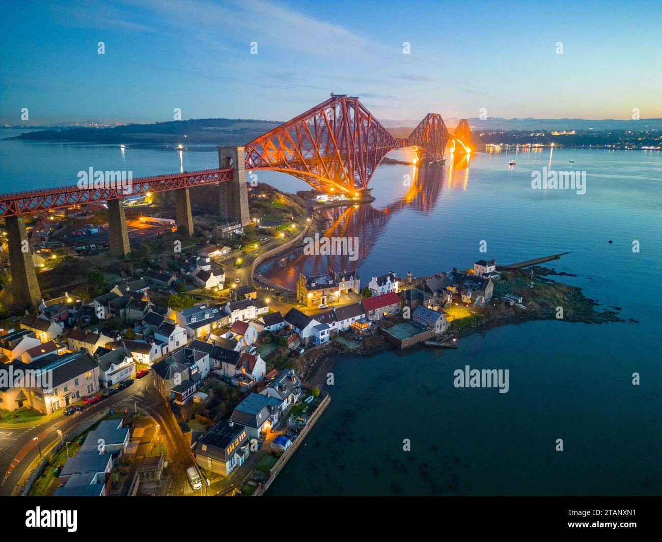 Aerial view from drone at night of North Queensferry village beside the Forth Bridge crossing the Firth of Forth, Fife, Scotland, UK Stock Photo