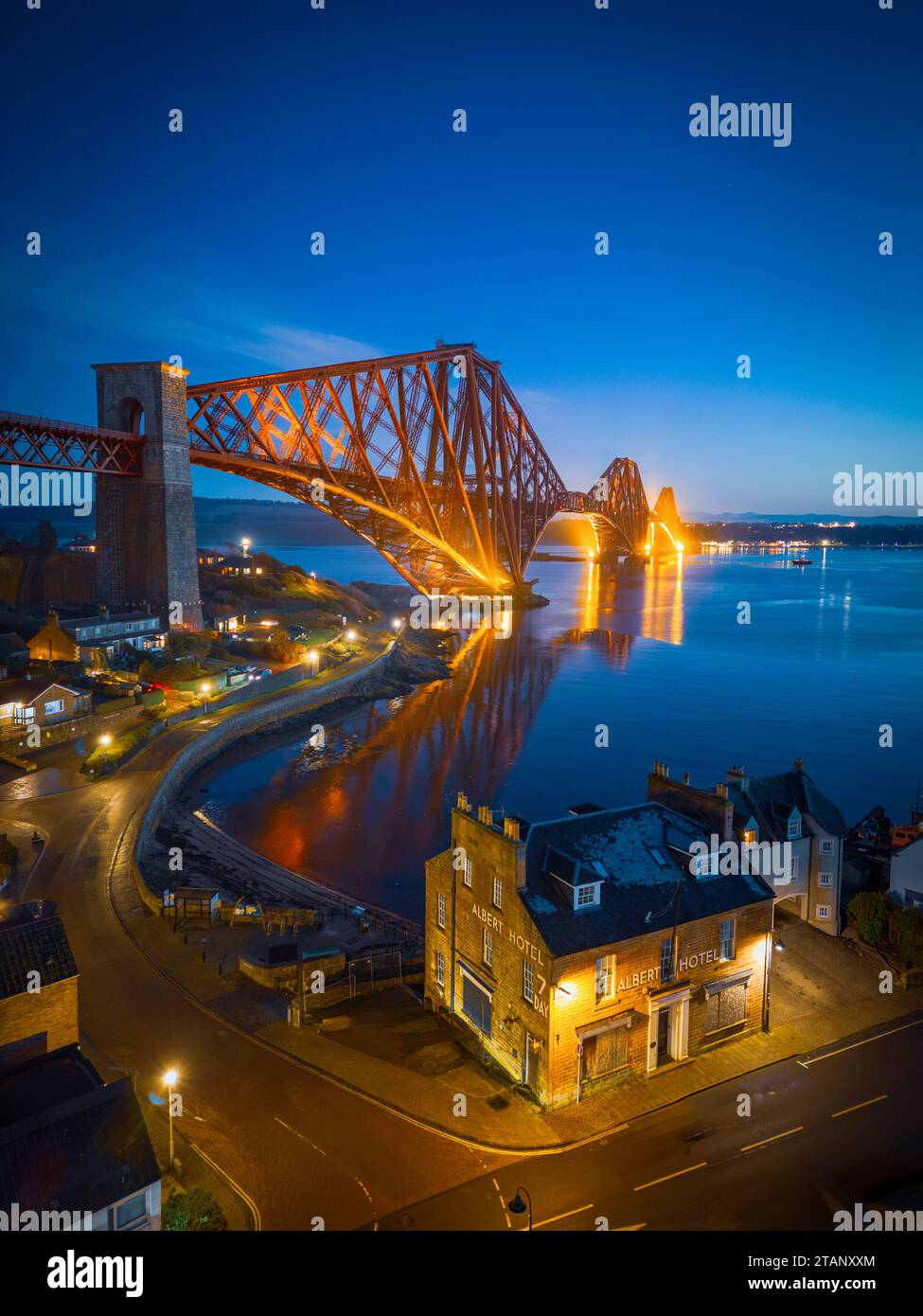 Aerial view from drone at night of North Queensferry village beside the Forth Bridge crossing the Firth of Forth, Fife, Scotland, UK Stock Photo