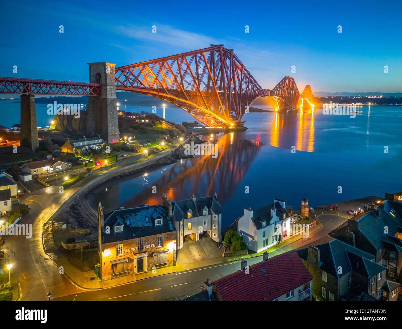 Aerial view from drone at night of North Queensferry village beside the Forth Bridge crossing the Firth of Forth, Fife, Scotland, UK Stock Photo