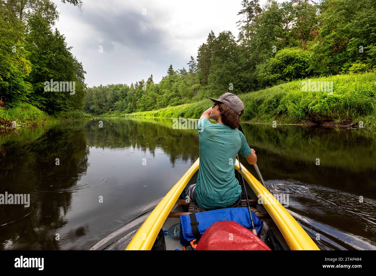 Tourist on a canoe, boat trip on Salaca river, exploring spectacular nature, Devonian red sandstone cliffs and lush forests, Mazsalaca, Latvia Stock Photo