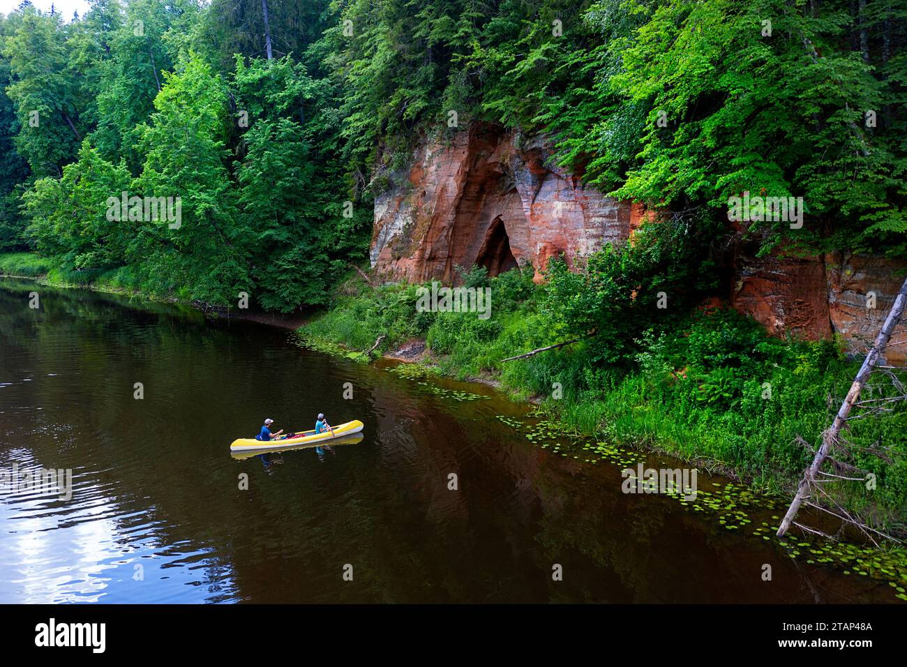 Tourists on a canoe, boat trip on Salaca river, exploring spectacular nature, Devonian red sandstone cliffs, caves and lush forests, Mazsalaca, Latvia Stock Photo