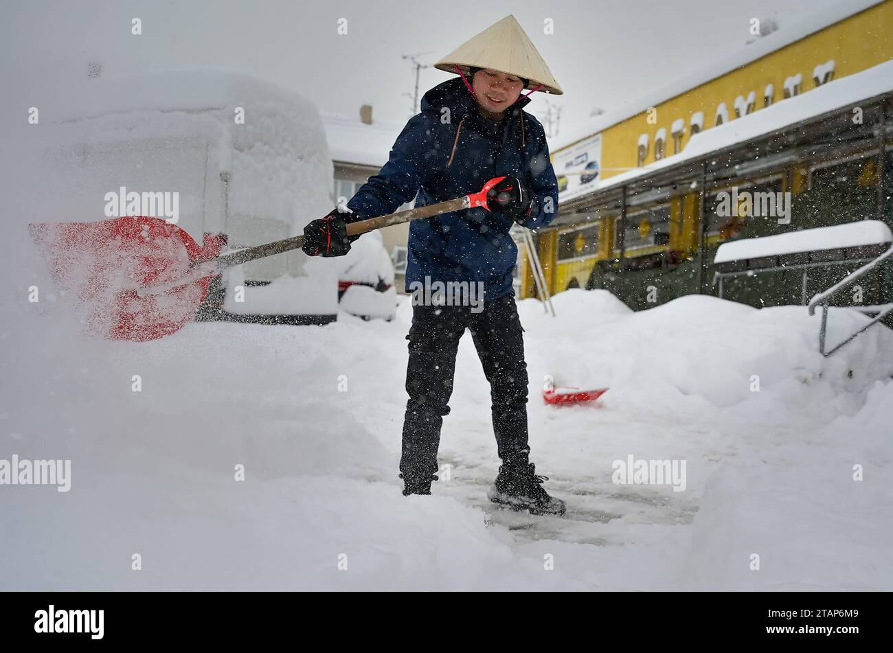 A Vietnamese shopkeeper removes snow from his shop in Kostelec u Jihlavy, Jihlava region, Czech Republic, December 2, 2023. (CTK Photo/Lubos Pavlicek) Stock Photo