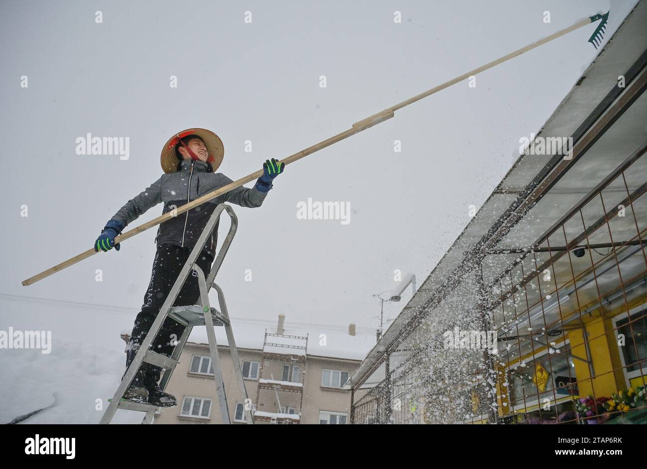 A Vietnamese shopkeeper removes snow from his shop in Kostelec u Jihlavy, Jihlava region, Czech Republic, December 2, 2023. (CTK Photo/Lubos Pavlicek) Stock Photo