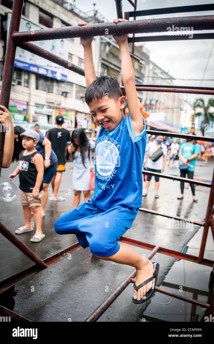 A young Filipino boy plays on a metal frame in Tondo, Manila, The Philippines. Stock Photo