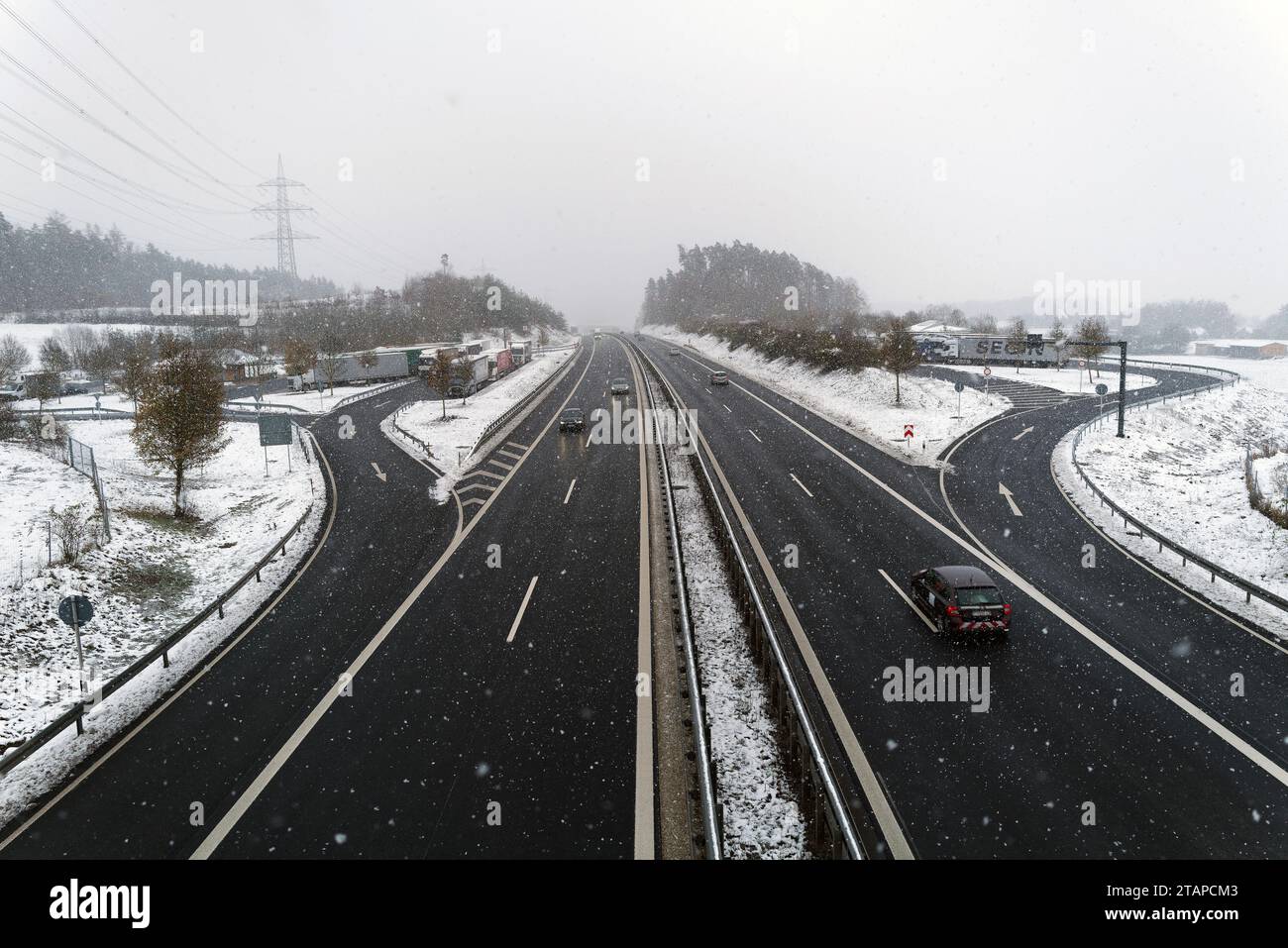 Coburg, Germany. 2nd December 2023. Cold weather in northern Bavaria after heavy snowfalls as cars pass under a footbridge and lorries take a break from the difficult driving conditions. Credit: Clearpiximages/Alamy Live News Stock Photo