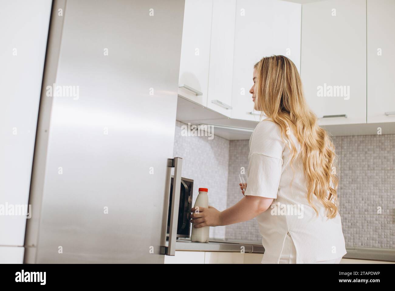 Young woman taking gallon of milk from refrigerator in kitchen Stock Photo Alamy